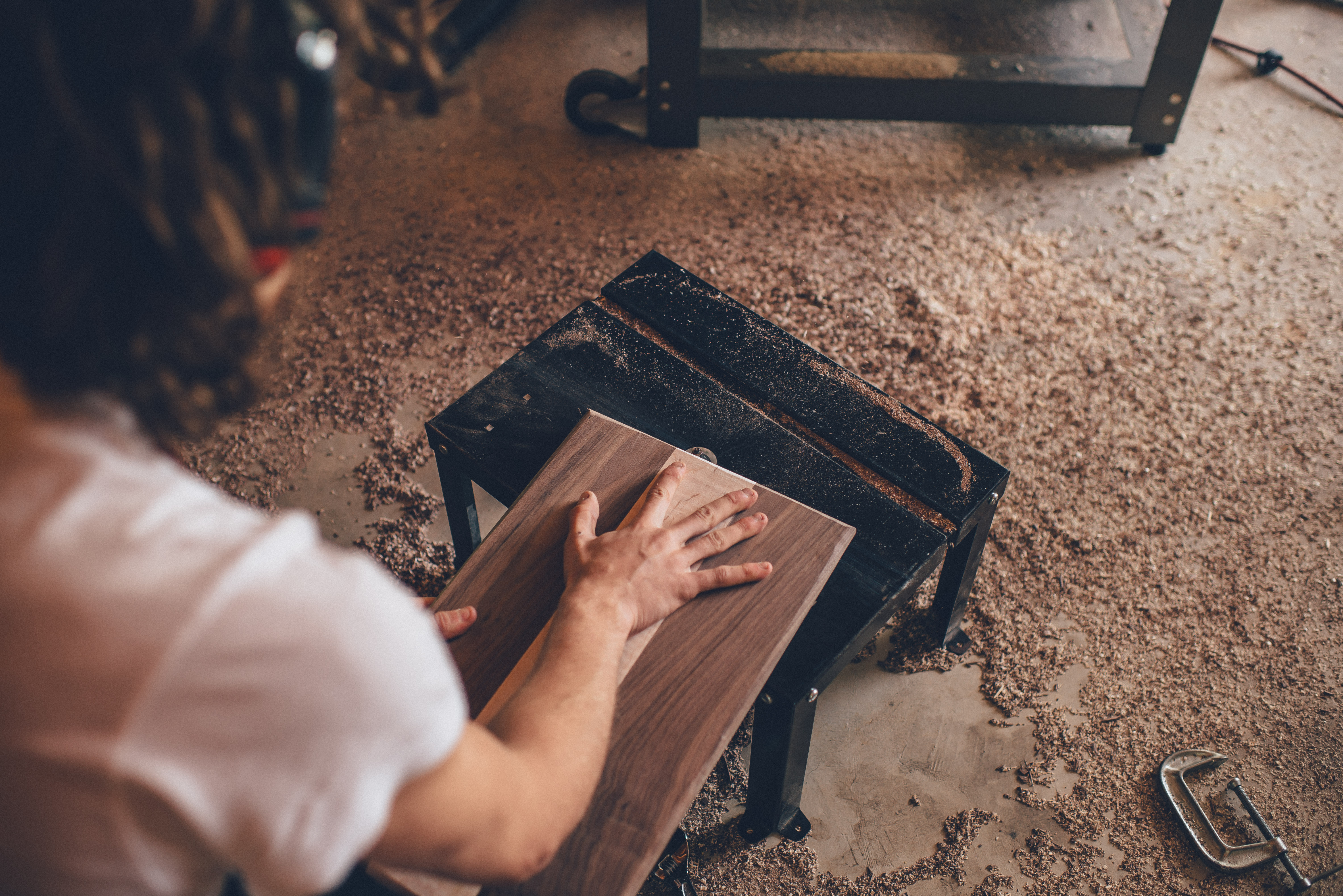 A person fitting a wooden part on a workshop workbench, illustrating hands-on fabrication