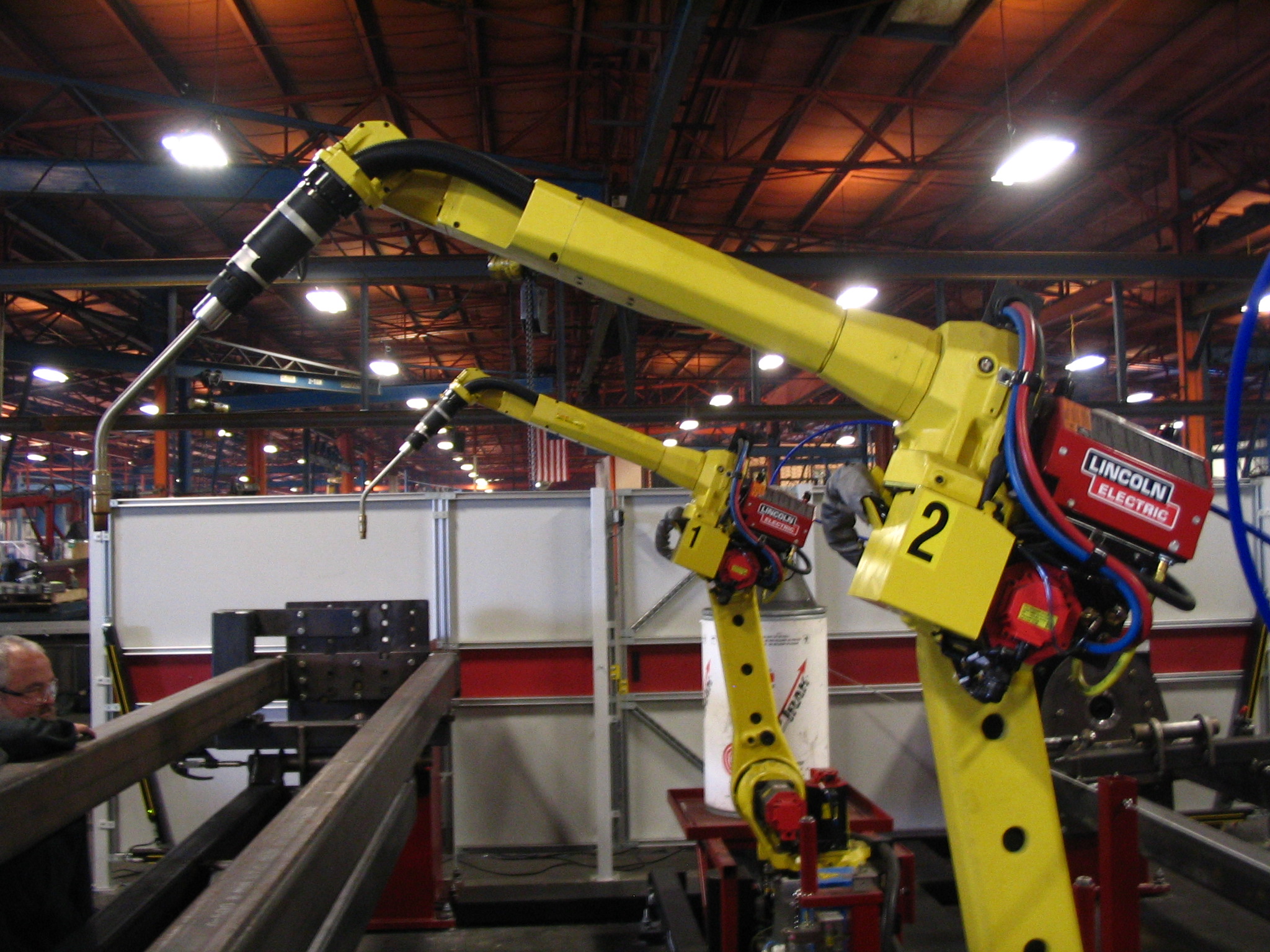 Yellow industrial welding robots in a factory cell, illustrating debugging a physical system